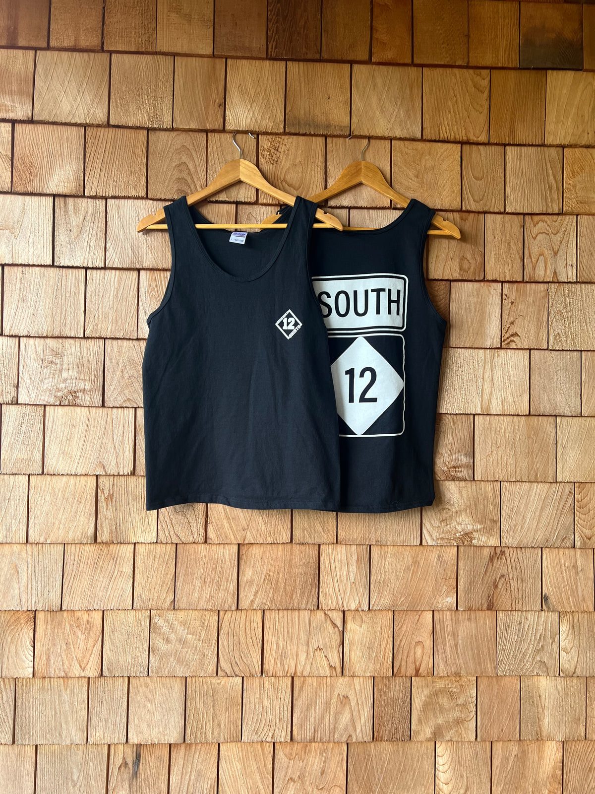 Black tank top with a white graphic on a wooden wall