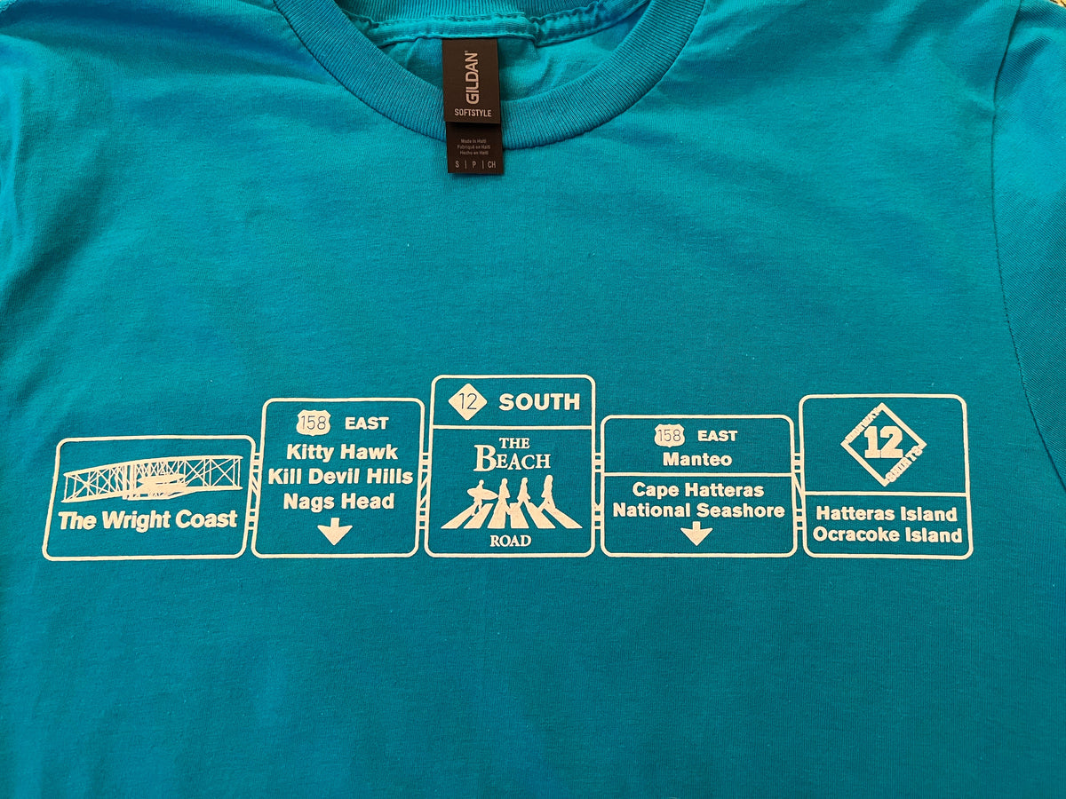 Blue t-shirt with white graphic designs resembling road signs on a plain background