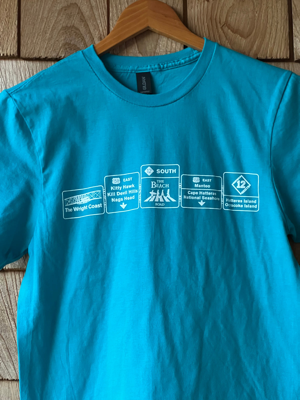 Blue t-shirt with brand logos on a wooden surface