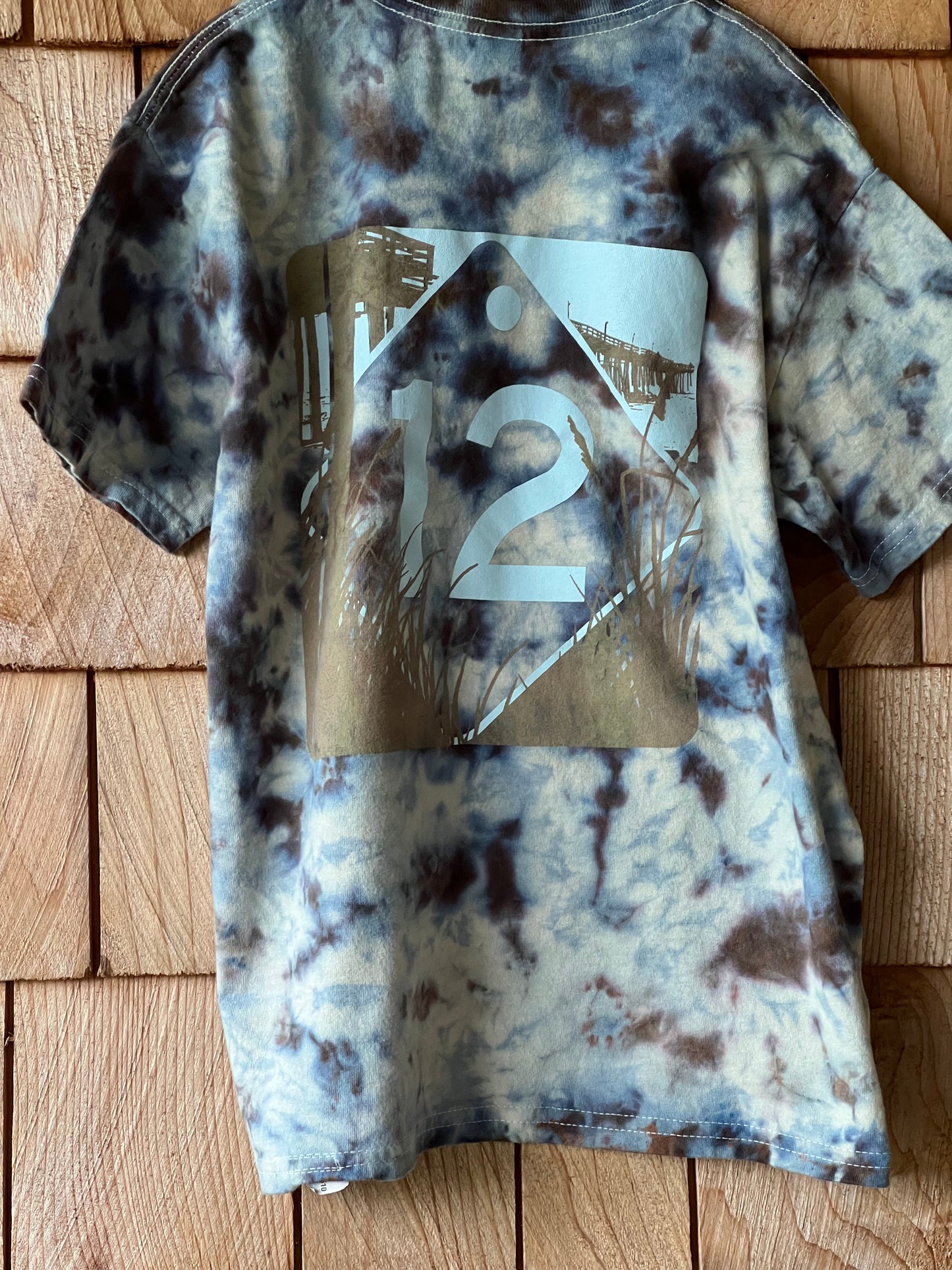 Tie-dye patterned shirt with a brand logo on a wooden surface