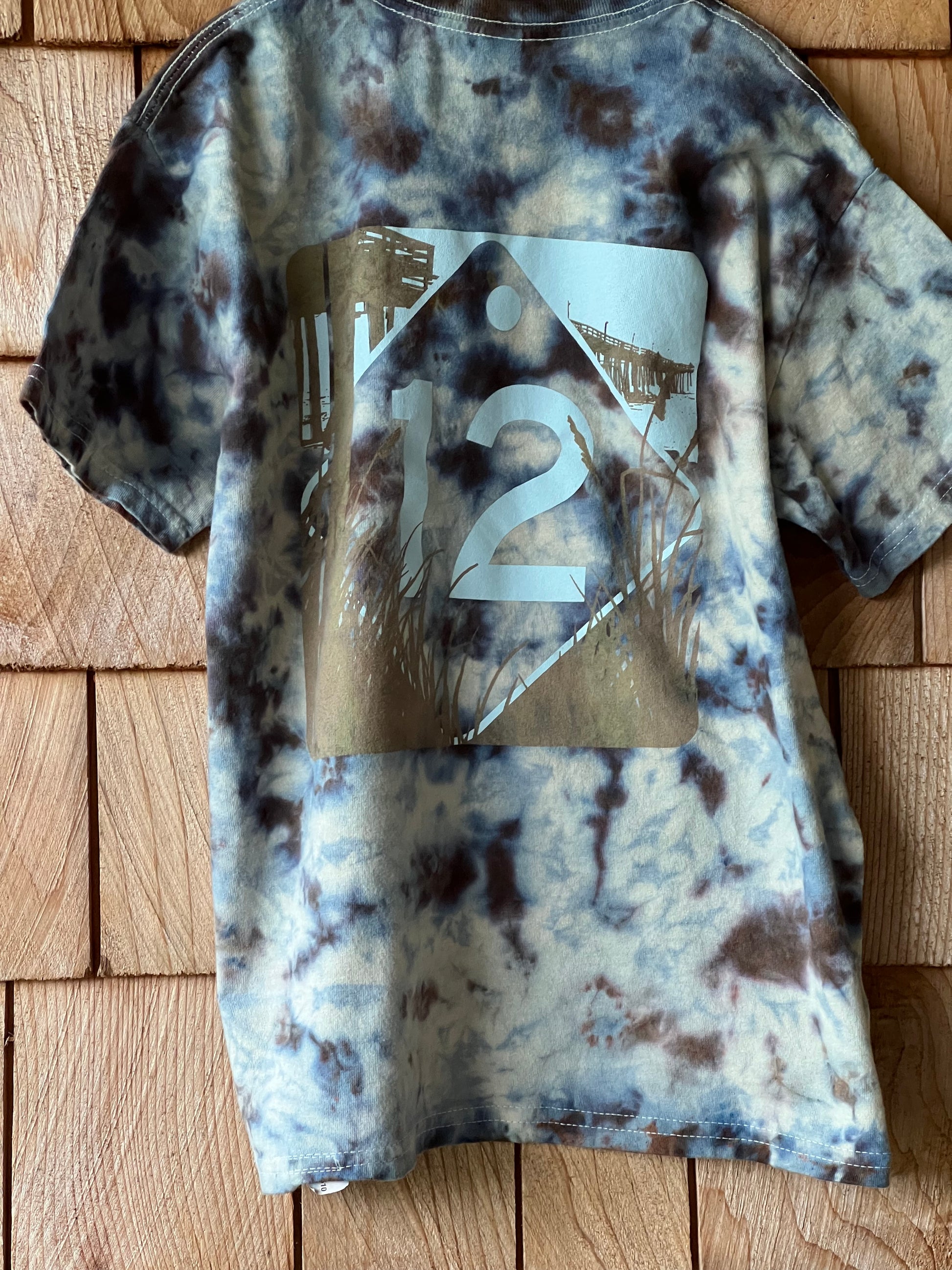 Tie-dye patterned shirt with a brand logo on a wooden surface