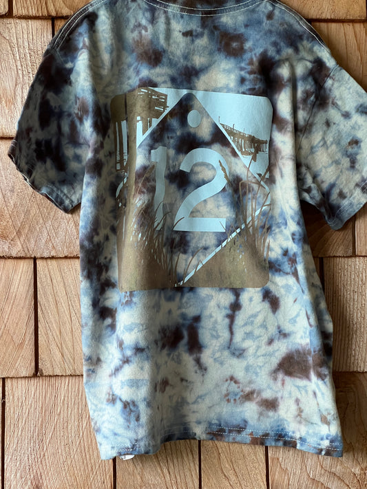 Tie-dye patterned shirt with a brand logo on a wooden surface