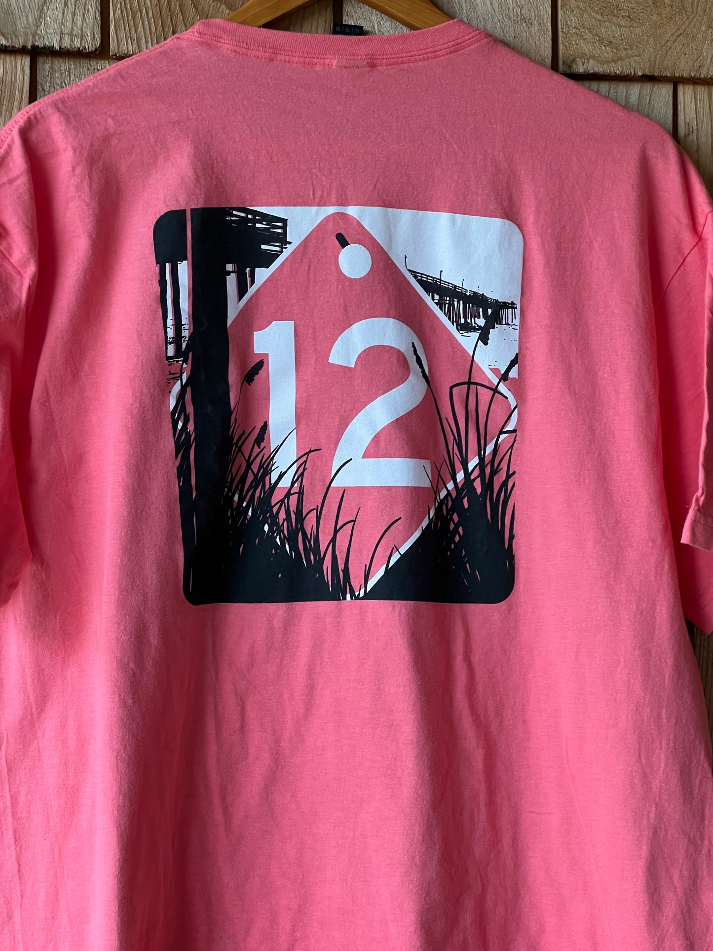 Pink t-shirt with a graphic design on a wooden surface