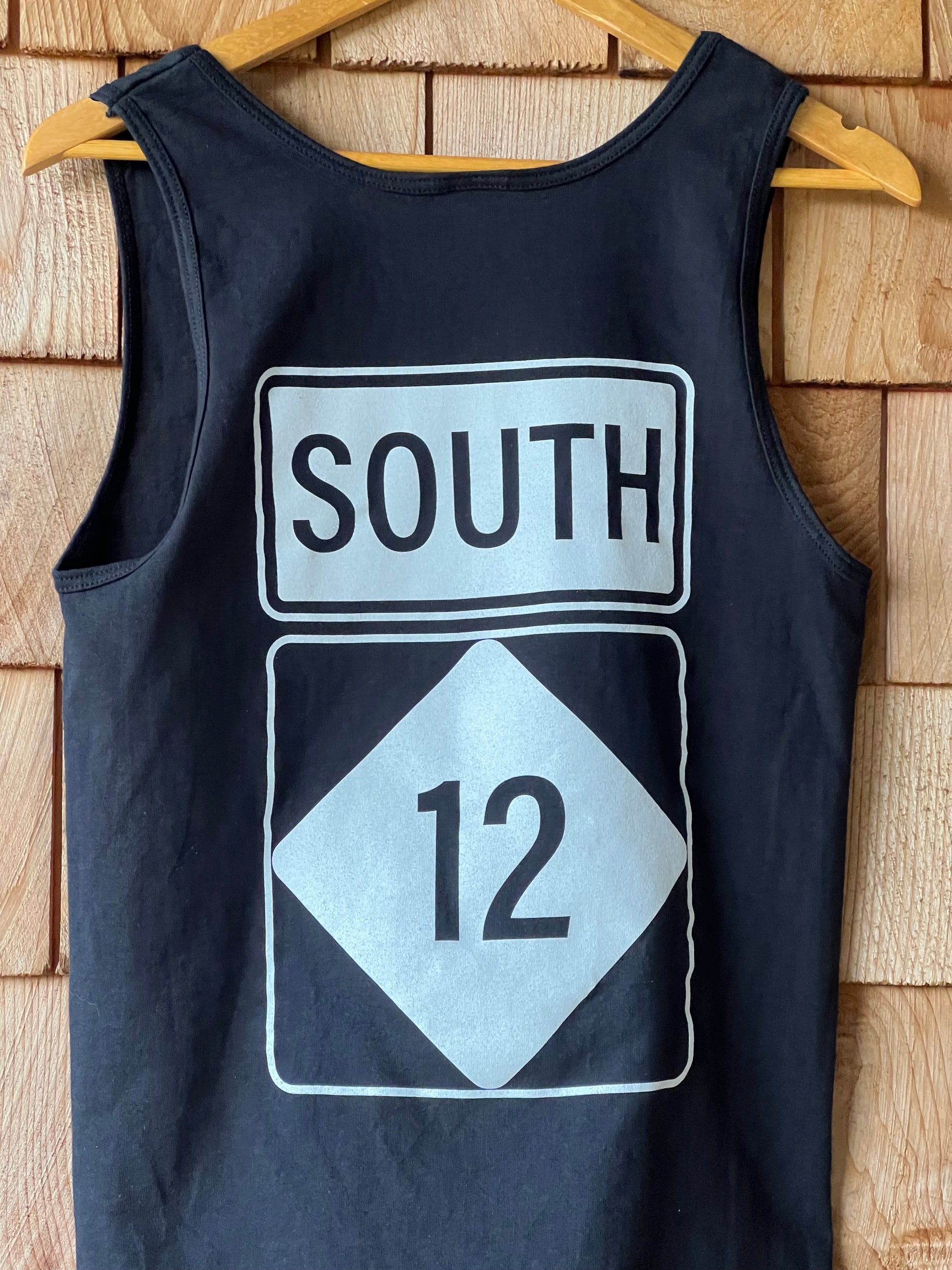 Black tank top with road sign graphics on a wooden surface