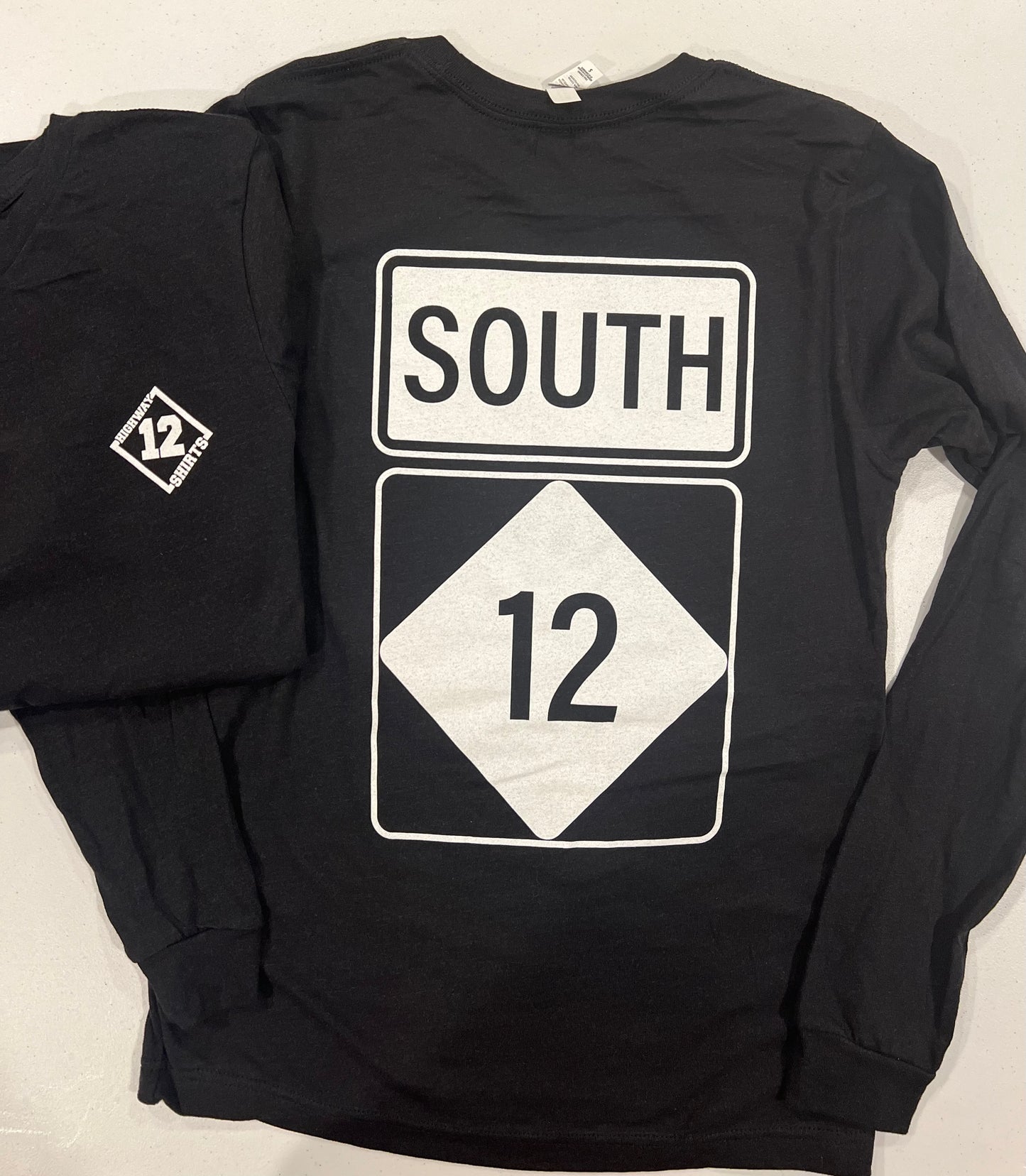 Black long-sleeve shirt with 'SOUTH 12' design on a light gray background