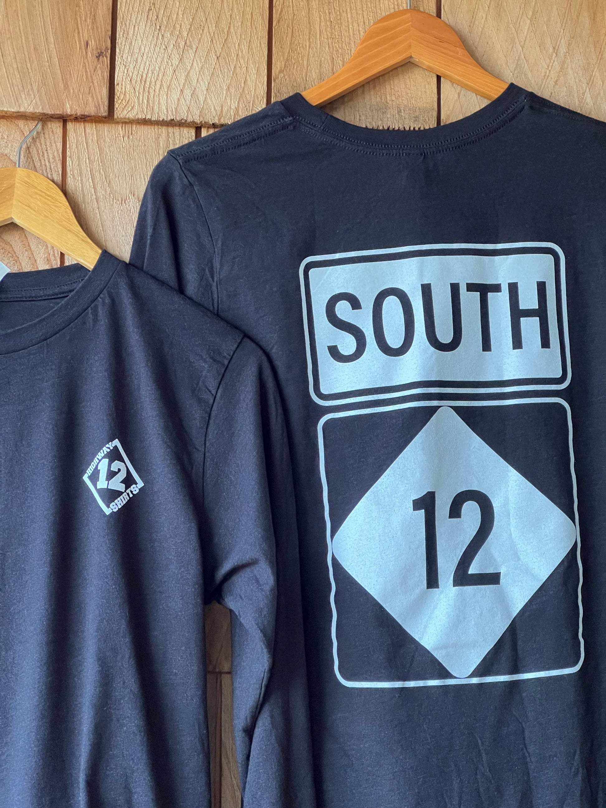 Black long sleeve shirt with 'SOUTH' and number '12' design on a wooden surface