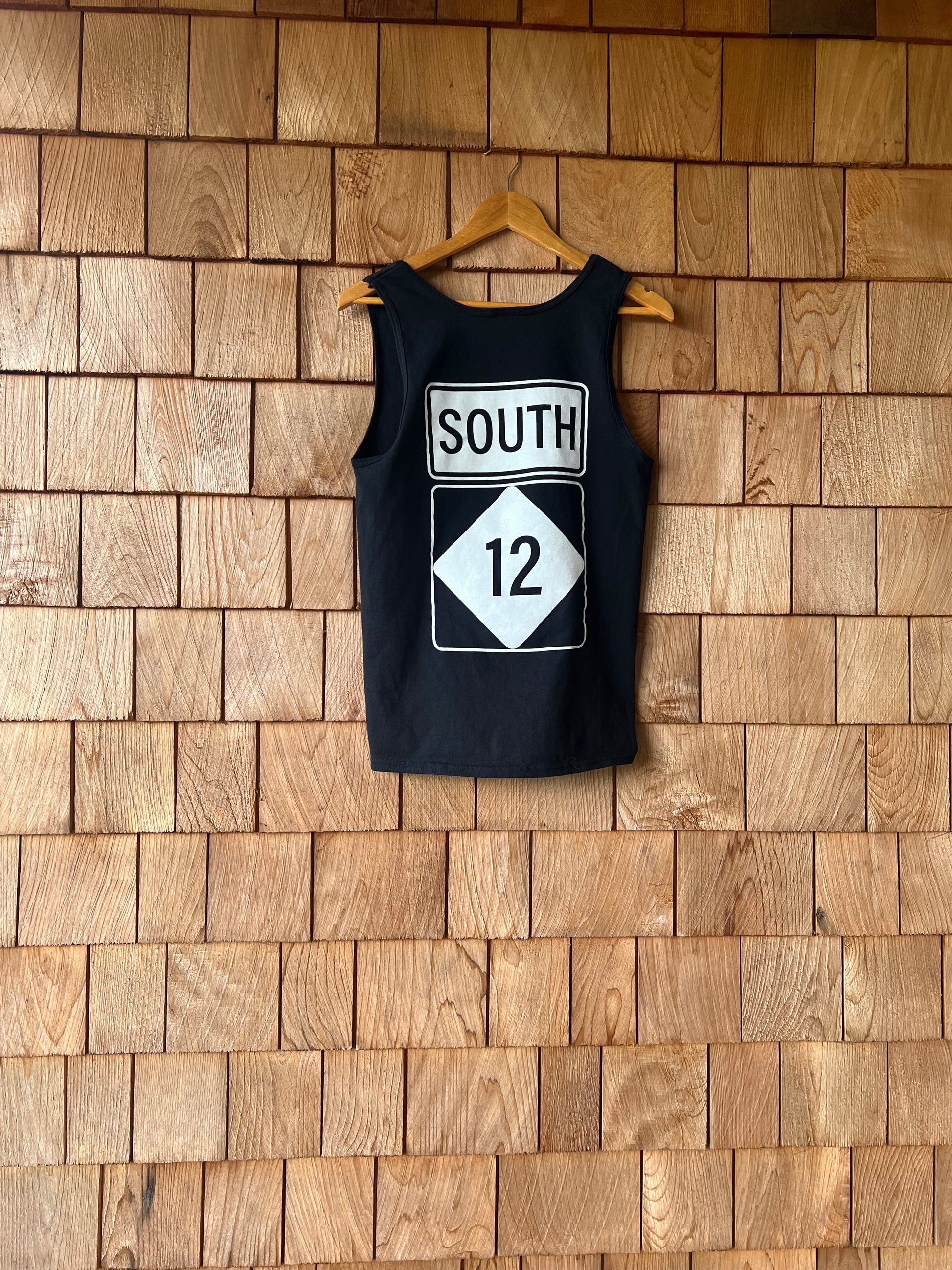 Black tank top with a white graphic on a wooden floor