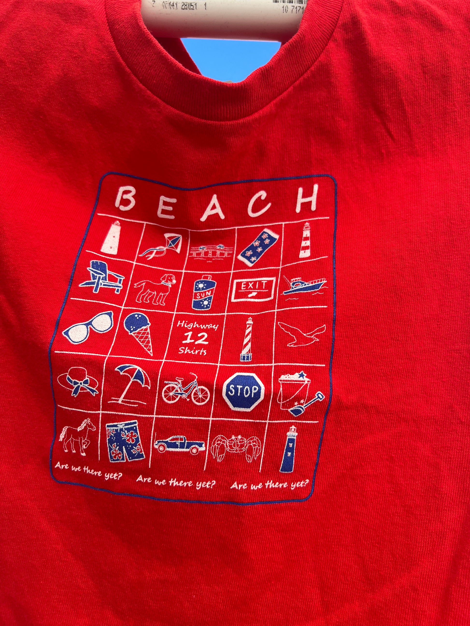 Red shirt with beach-themed graphic design on a blue background