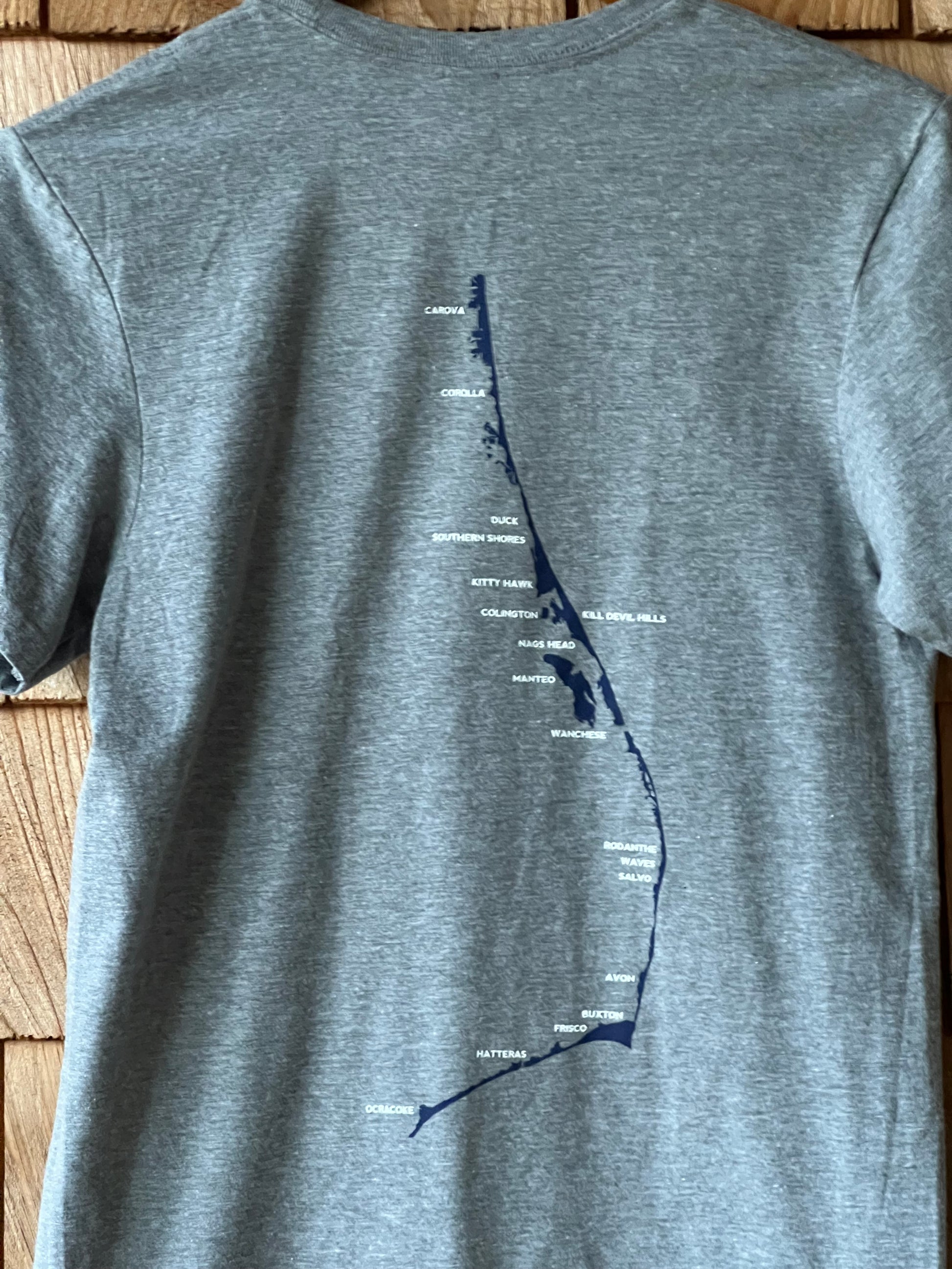 Gray t-shirt with a blue graphic design on a wooden surface