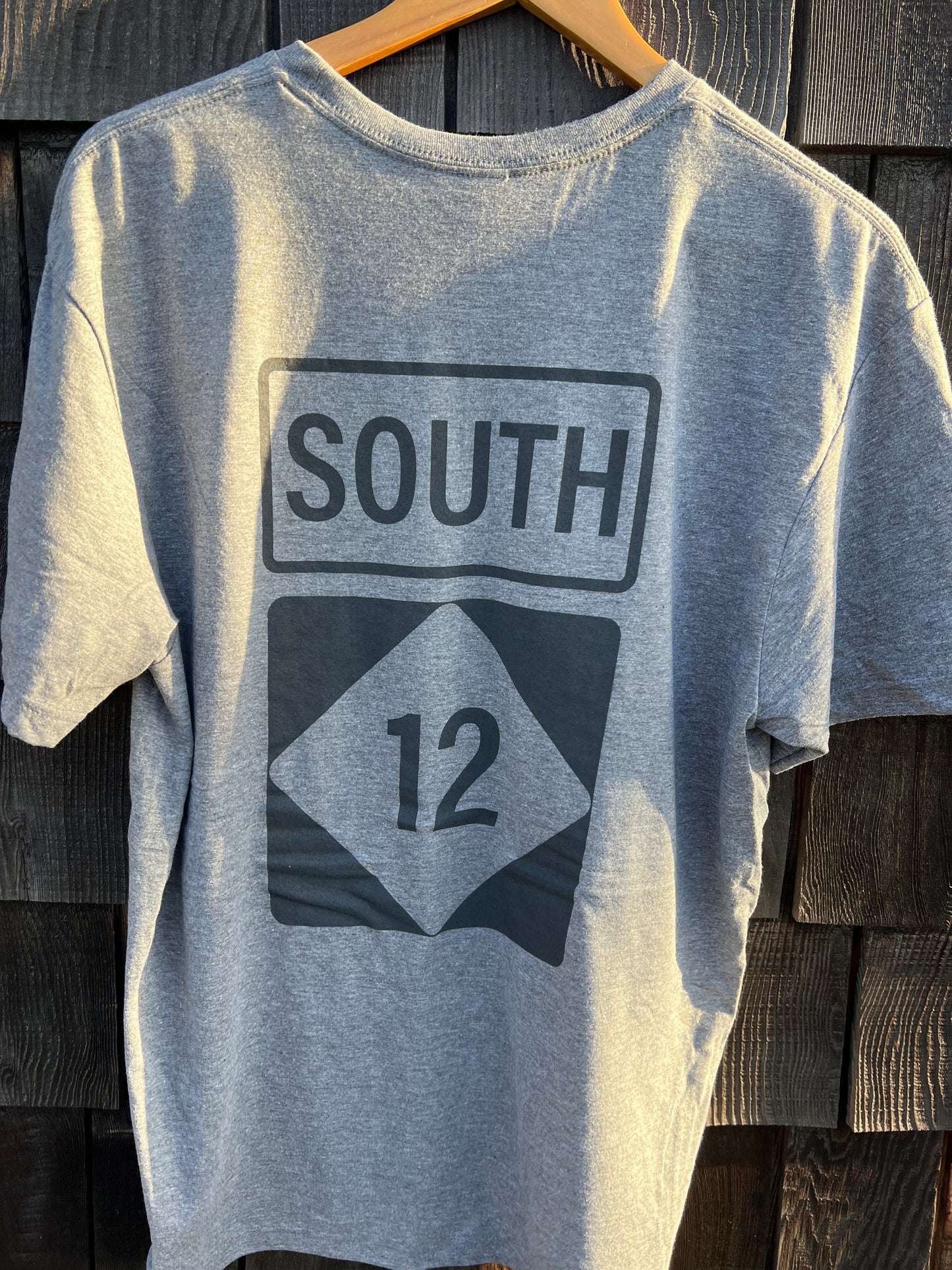 Gray t-shirt with 'SOUTH' and number '12' design on a wooden background