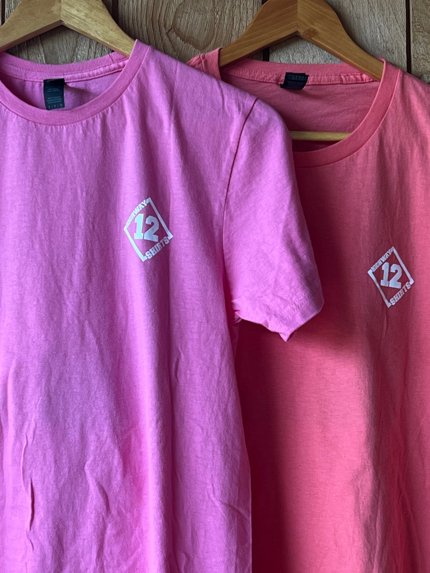 Pink t-shirt with a logo on a wooden hanger