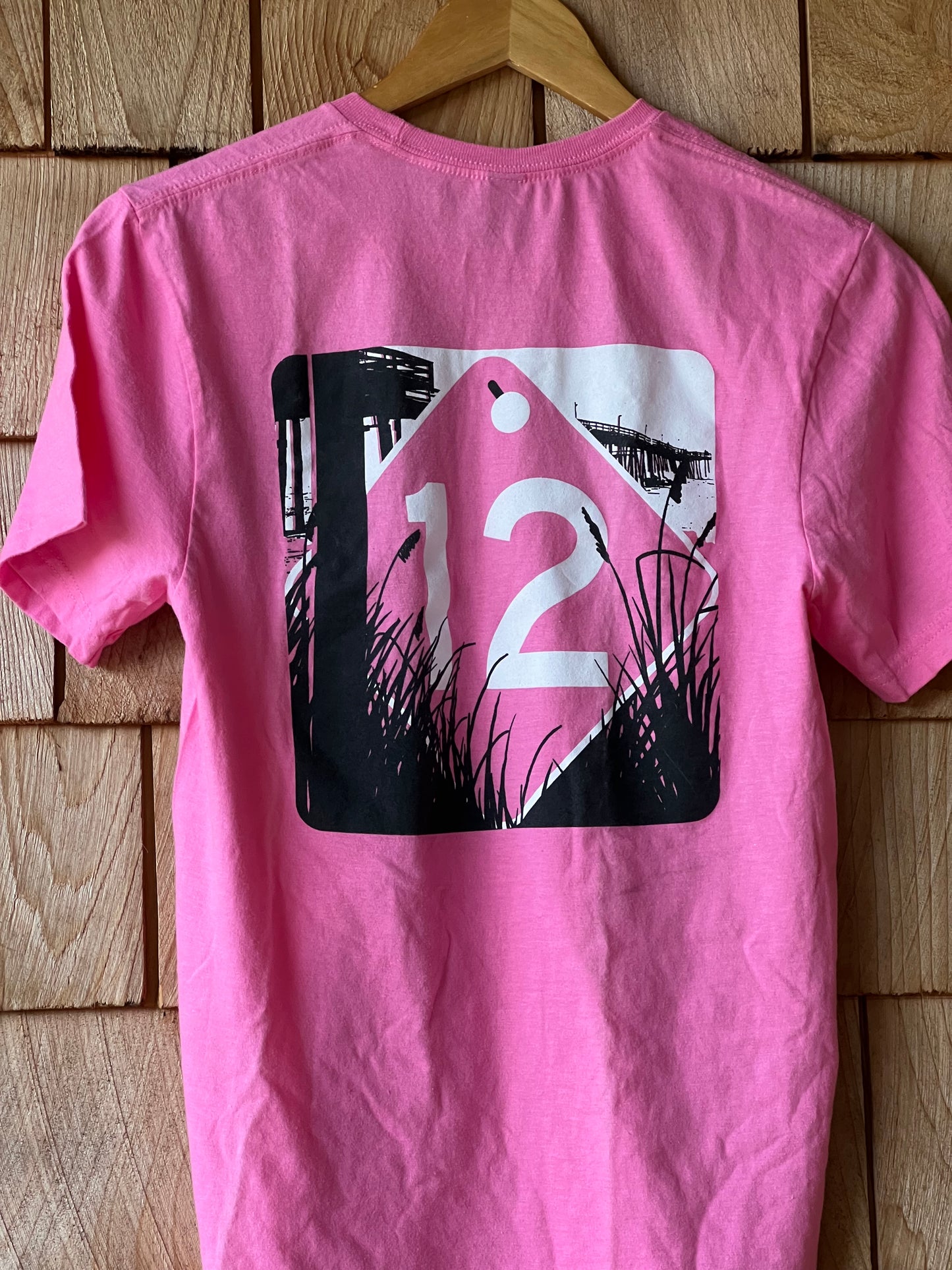 Pink t-shirt with a graphic design on a wooden surface