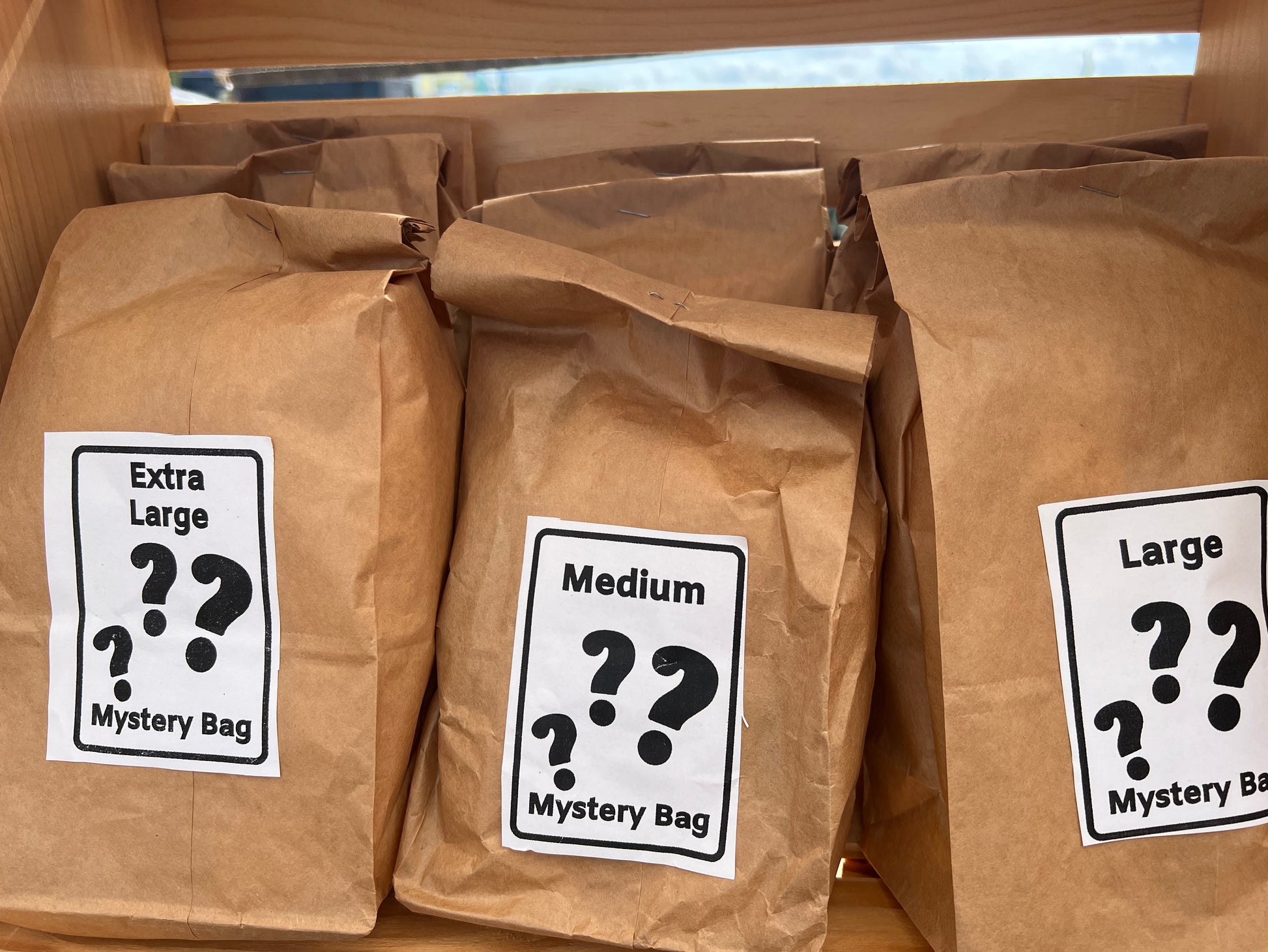 Three brown paper bags with size labels and question marks, indicating mystery contents.