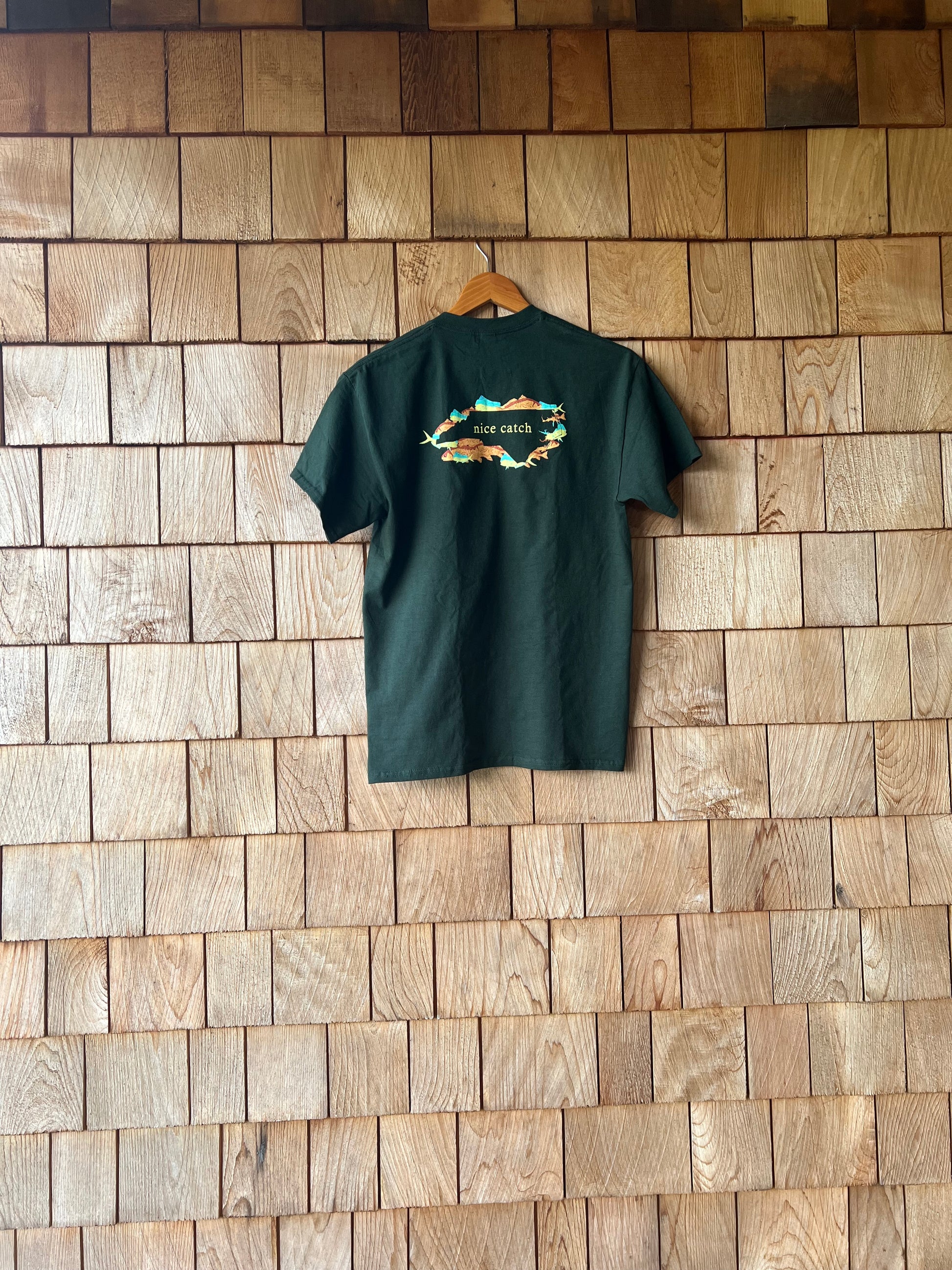 Green t-shirt with a colorful design on a wooden floor