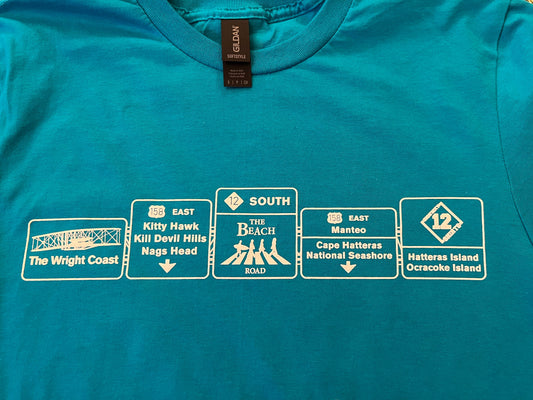 Blue t-shirt with white graphic designs resembling road signs on a plain background