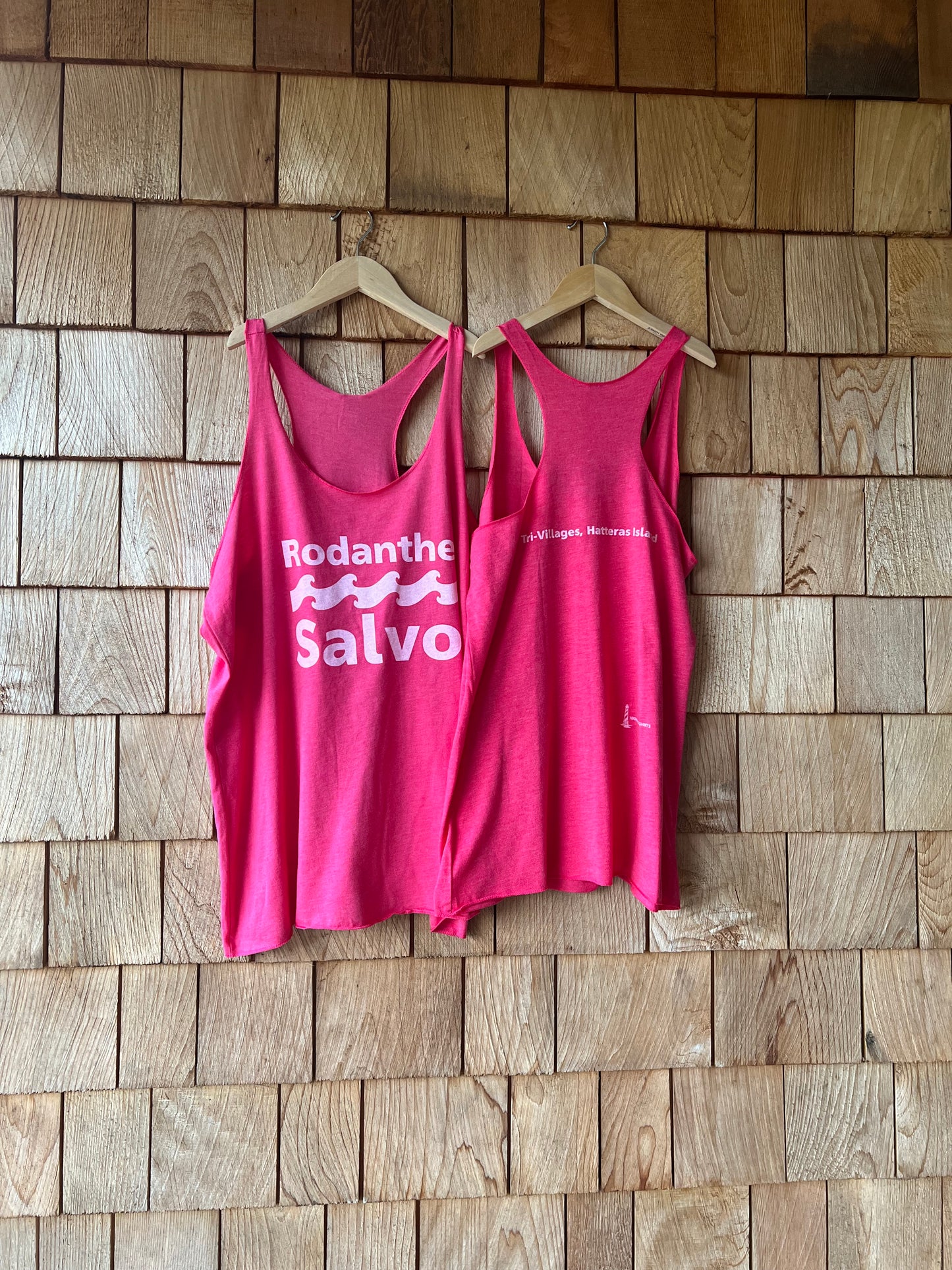 Two pink tank tops with text on a wooden floor