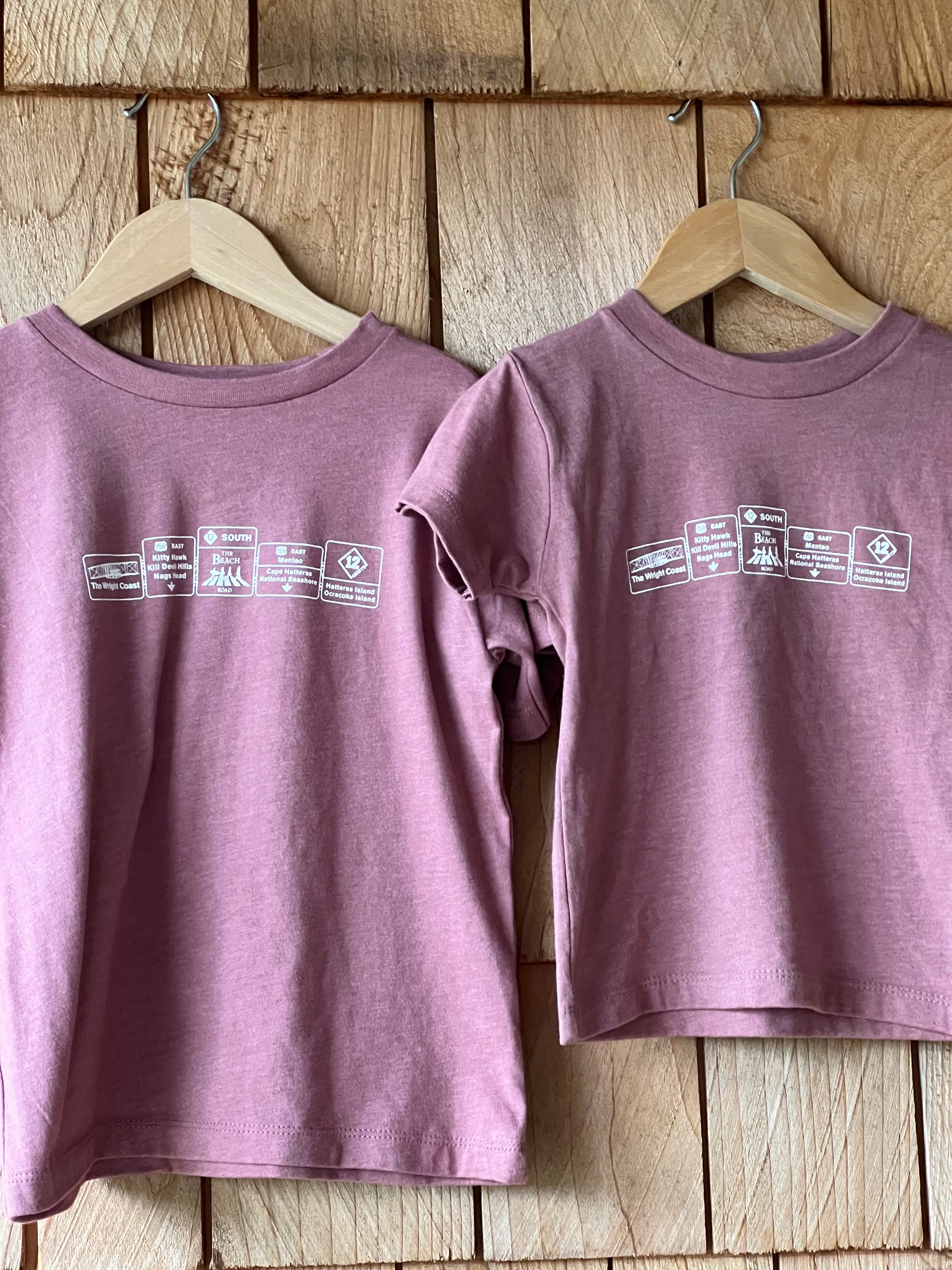 Two purple tank tops with labels on a wooden surface