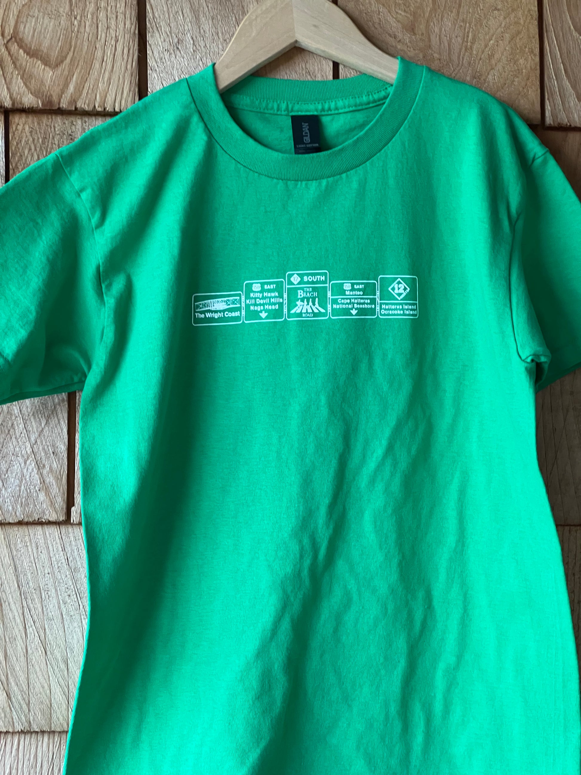 Green t-shirt with white text on a wooden surface
