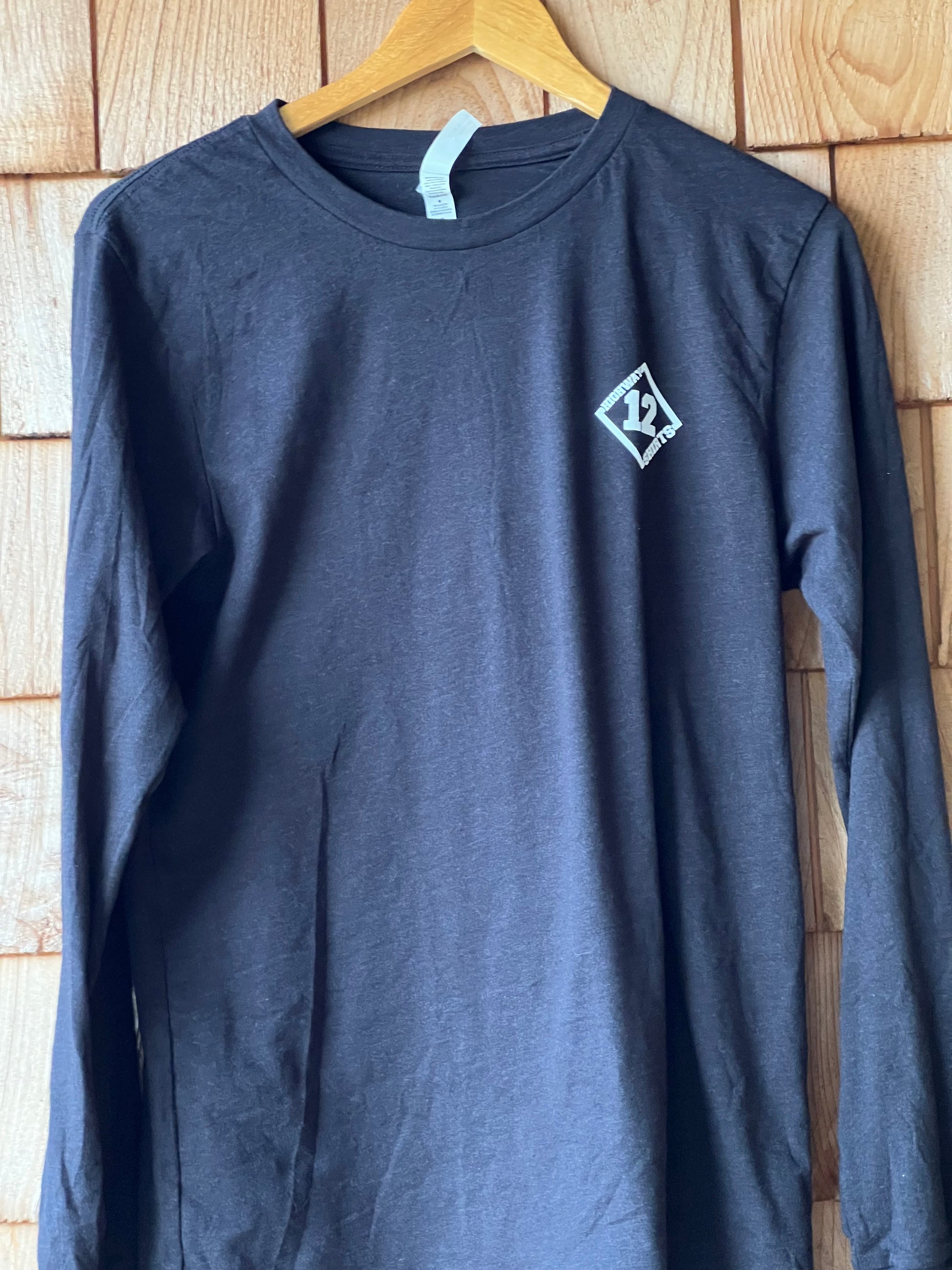 Black long sleeve t-shirt with a logo on a wooden surface