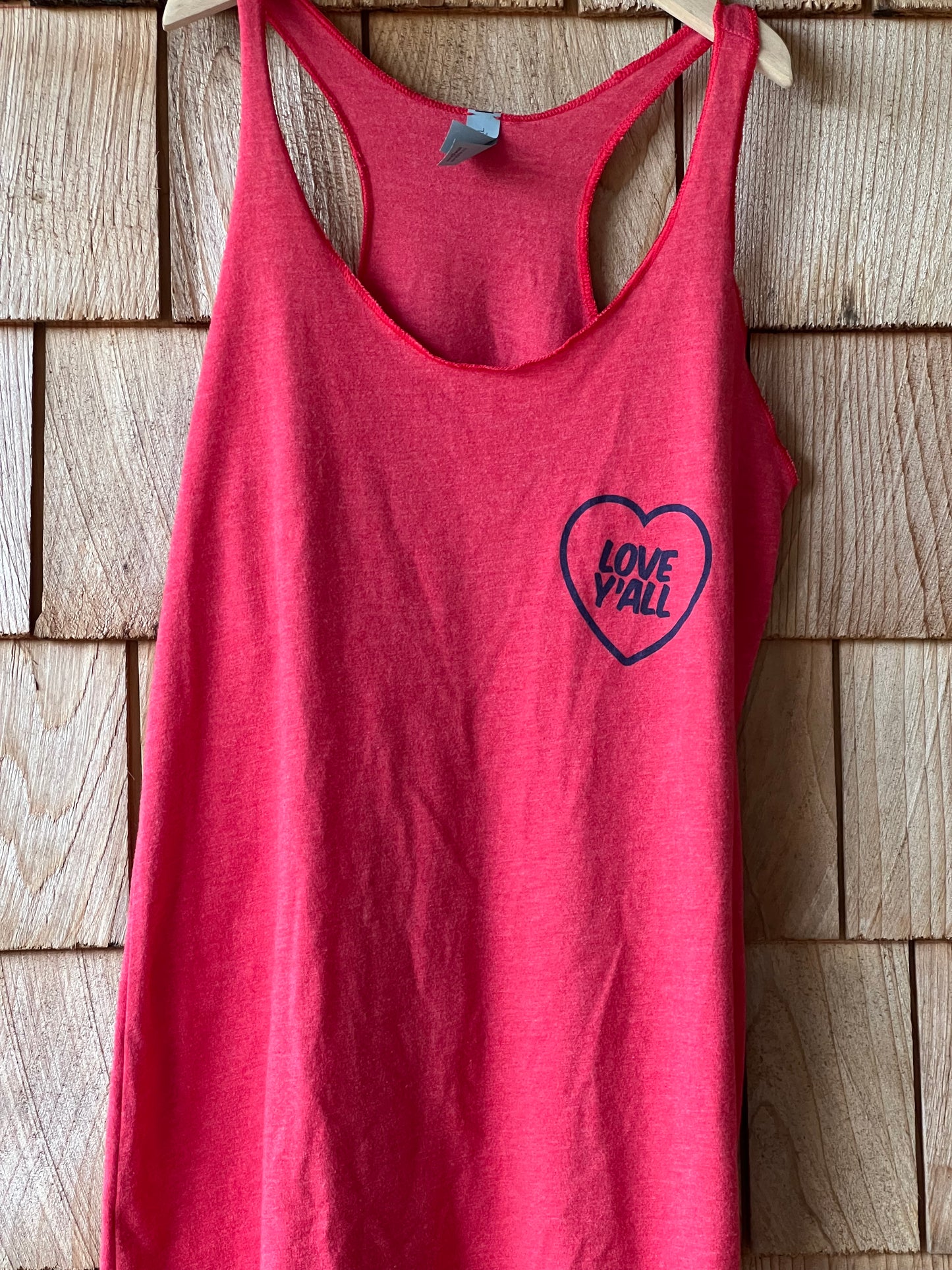 Red tank top with a heart-shaped logo on a wooden surface