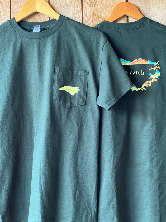 Green t-shirt with a small pocket design on a wooden surface