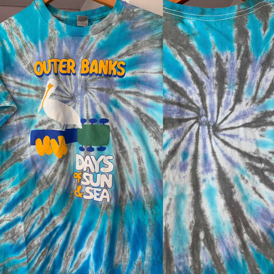 Tie-dye t-shirt with 'Outer Banks' and 'Days of Sun & Sea' text, featuring a pelican and sunglasses design.